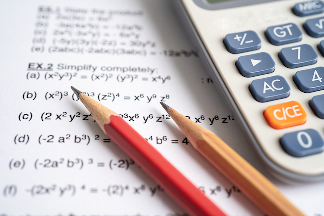 Pencil and calculator on mathematic formula exercise test paper in education school.